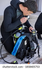 Scuba Diver Kitting Up And Checking His Gear, Testing Regulator And Pressure Gauge