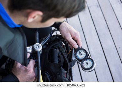 Scuba Diver Kitting Up And Checking The Pressure Gauge, Close Up Of Hand Holding Equipment Over Shoulder Shot.