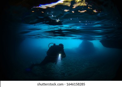 scuba diver underwater exploring caves with a torch light - Powered by Shutterstock