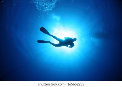 Scuba Diver underwater silhouettes against sun - Powered by Shutterstock