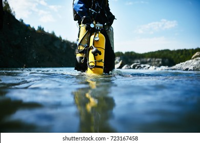 Scuba Diver Walking Towards Water Depth And Carrying Diving Equipment