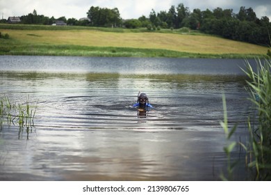 A scuba diver in a wet suit prepares to immerse in a pond