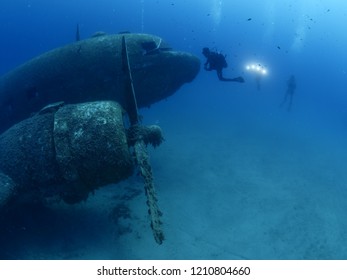 scuba divers exploring airplane wreck underwater