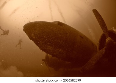 scuba divers exploring airplane wreck underwater
