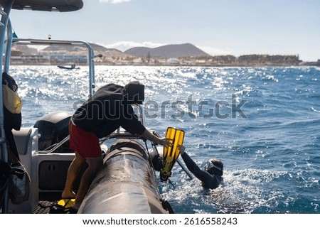 Scuba diving instructor helping diver remove fins after diving in the ocean from boat