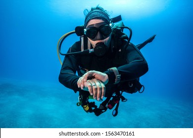 Scuba Instructor checks Dive Computer in the Deep Blue - Shutterstock ID 1563470161