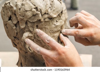 sculptor creates a bust and puts his hands clay on the skeleton of the sculpture. Close-up