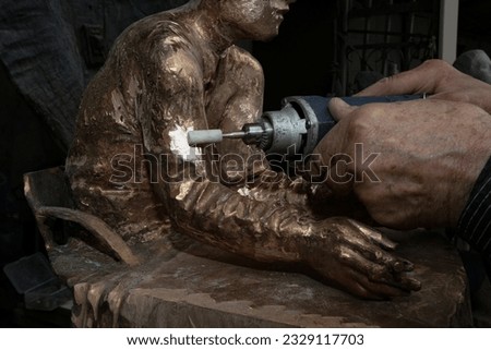 the sculptor grinds a bronze sculpture with a tool close-up shot