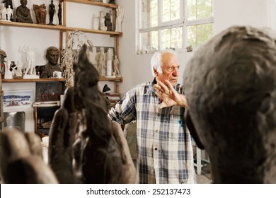 Sculptor in studio raising palm while looking sideways
