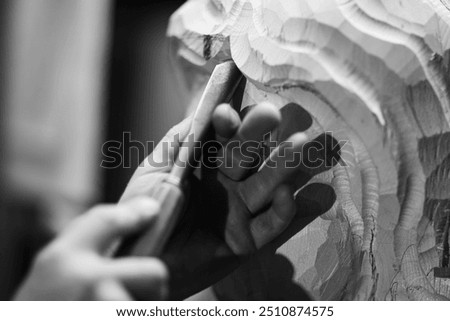 Sculptor is using a mallet and chisel to carve a large piece of wood in a workshop, with wood chips flying through the air