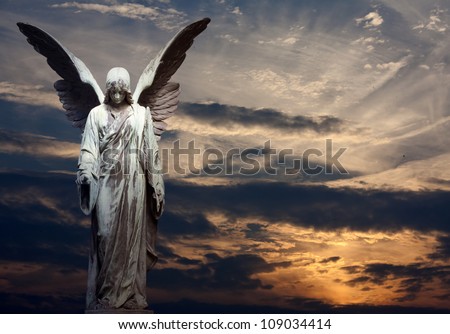 Sculpture of angel on cemetery in sunset background