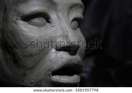 Sculpture of asian woman, wet clay, face detail , on black background