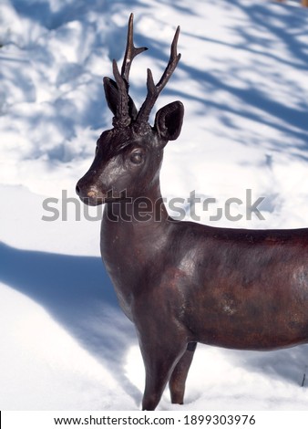 Sculpture of bronze roe deer in the snow.