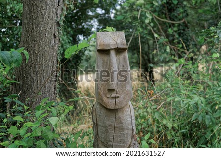 A sculpture carving on a dead tree stump of an artistic face in the English countryside