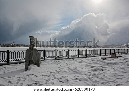 Sculpture of an eagle made of stone on the embankment of a city pond.