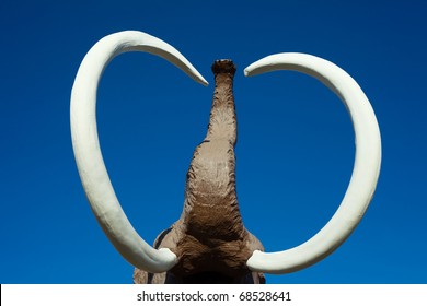 Sculpture Of Extinct Wooly Mammoth With Impressive Tusks And Trunk.