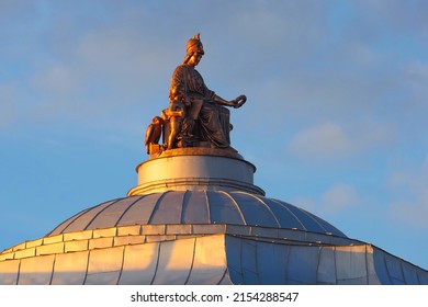 Sculpture of the goddess Minerva crowning arts and sciences on top of the dome of the Academy of Arts in Saint Petersburg, Russia at sunset