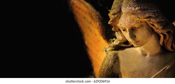 Sculpture Of Gold Angel With Wings Against Dark Background 