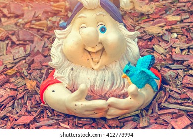 Sculpture small gnome with a blue bird in red wooden sawdust - Powered by Shutterstock