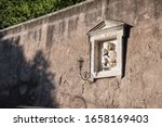 Sculpture of the Virgin Mary and baby Jesus on the wall, street of Rome, Italy. In the afternoon