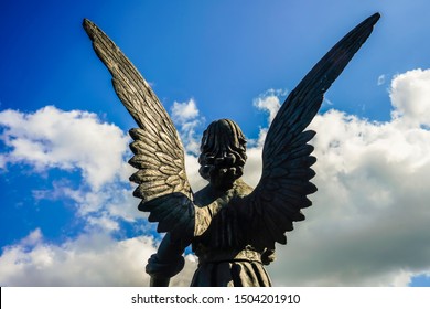 Sculpture of a wing angel on blue sky background. back view. 