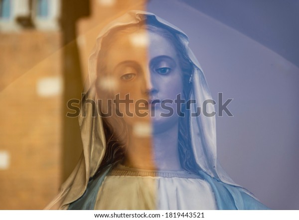 Sculpture of a woman with opposite\
colors reflected on the glass infront, dividing her in\
half