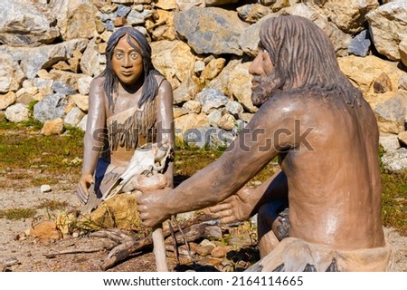 Sculptures of primitive people in the green forest.