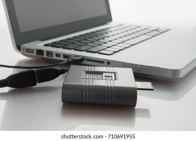 SD card and card reader conected to laptop close-up.