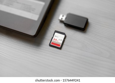 SD memory card on table beside laptop computer and card reader