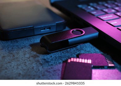 SD memory cards, USB flash drive, hard disk drive and laptop on dark grey table, closeup