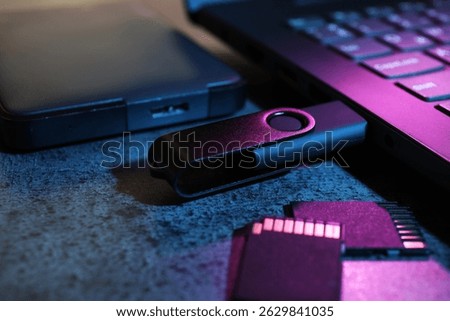 SD memory cards, USB flash drive, hard disk drive and laptop on dark grey table, closeup