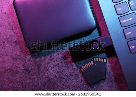 SD memory cards, USB flash drive, hard disk drive and laptop on dark grey table, flat lay
