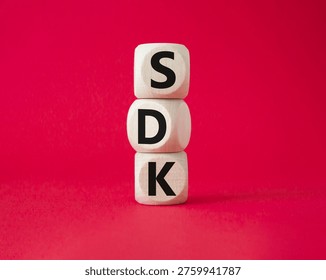 SDK - software development kit. Wooden cubes with word SDK . Beautiful red background. Business and software development kit concept. Copy space.