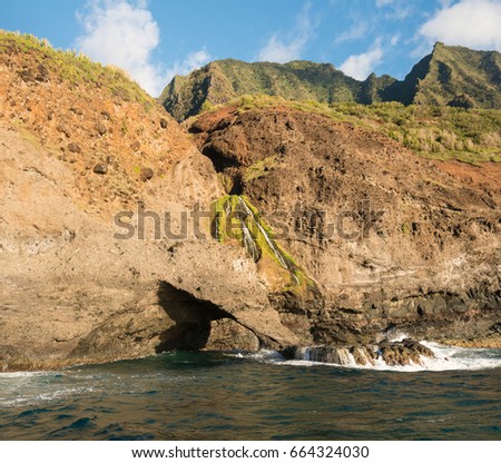 Sea arch and waterfall on Na Pali coastline in Kauai from sunset cruise
