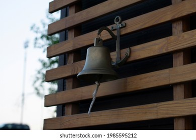 Sea Bell With Anchor Design And Lace Is Hanging On Wooden Wall. Welcome Dinner Bell