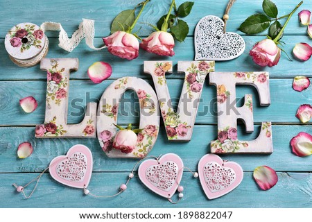 sea blue wooden background with vintage style letters forming word LOVE and roses