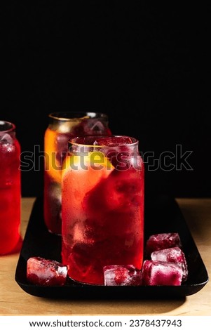 Sea breeze cocktail with frozen cranberries on a dark background.