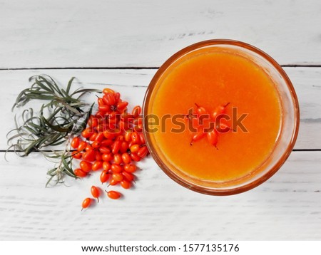 Sea buckthorn berries juice smoothie glass on white wooden background, top view. Sea buckthorn (Hippophae rhamnoides) organic juice & oil berry. Seabuckthorn juice, berries of sea buckthorn on table