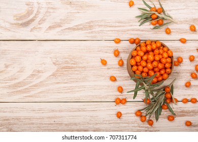 Sea buckthorn. Ripe fresh berries in bowl on white wooden background with copy space for your text. Top view
