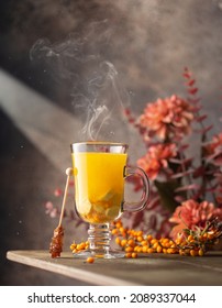 Sea Buckthorn Tea In A Glass With Fresh Berries,smoke And Autumn Flowers On Background.Close Up Of Healthy Hot Drink.