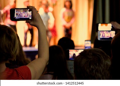 A Sea Of Parents’ Cell Phones Are Held High To Record Their Children’s Performance In A School Play.