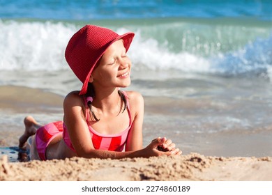 Sea Children Holiday. Beautiful Tann Girl Teen Sunbathing on Sea Sand Beach. Tanned Girl enjoy on Sea Wave Background.