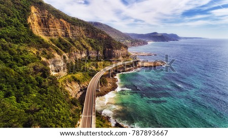 Sea cliff bridge at the edge of steep sandstone cliff on the Grand Pacific drive along pacific coast of Australia, NSW. Aerial view towards distant hill ranges on sunny summer day.