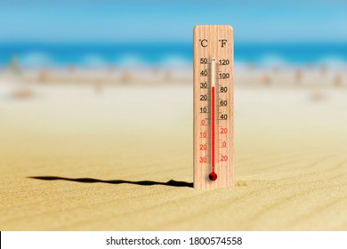 Sea coast at hot summer day. Wooden thermometer in the sand. Ambient temperature plus 31 degrees celsius
