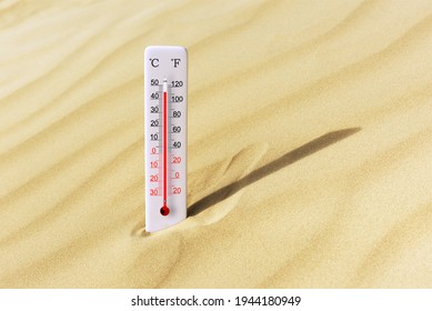 Sea coast at hot summer day. Celsius and fahrenheit scale thermometer in the sand. Ambient temperature plus 45 degrees celsius