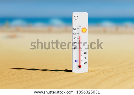 Sea coast at hot summer day. Fahrenheit scale thermometer in the sand shows plus 90 degrees 