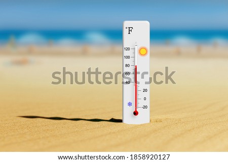 Sea coast at hot summer day. Fahrenheit scale thermometer in the sand shows plus 80 degrees 