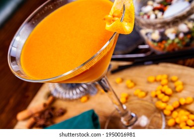 Sea ​​buckthorn Cocktail In Martini Glass On Wooden Table. Close Up