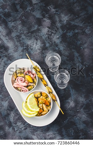 Sea cocktail - mussels, calamari, octopus and alcohol drink on dark stone background. Top view, copy space.