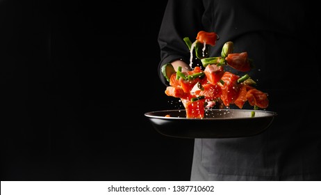 Sea cuisine, Professional cook prepares pieces of red fish, salmon, trout with vegetables.Cooking seafood, healthy vegetarian food and food on a dark background. Horizontal view. Banner